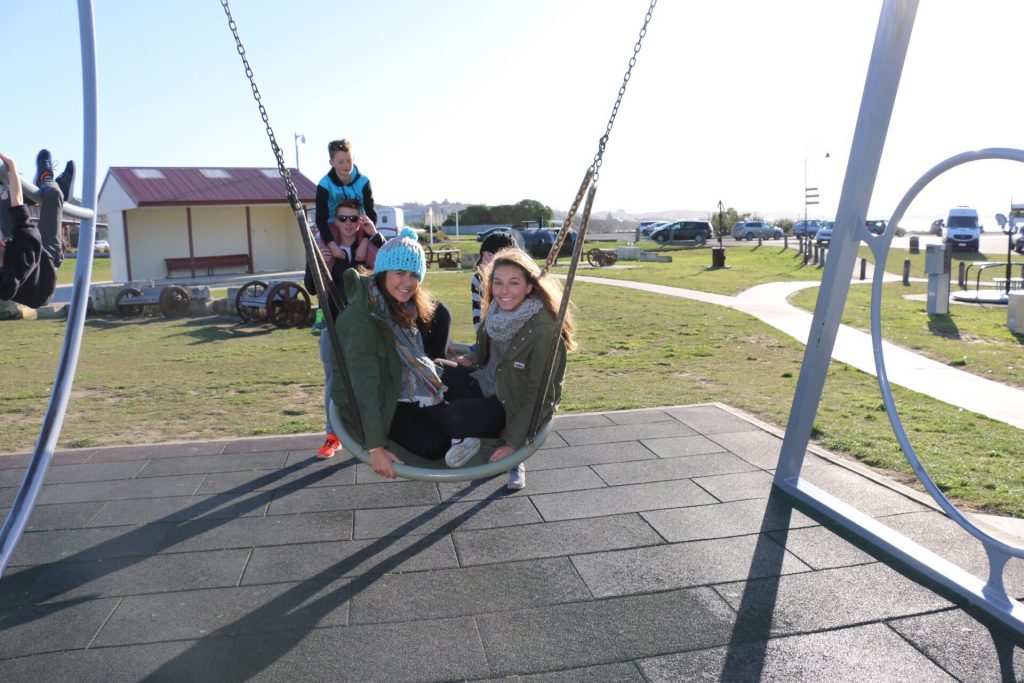 In the back, Jack holds his host family brother, Toby. The foreground pictures Laila and Ana on a swing.